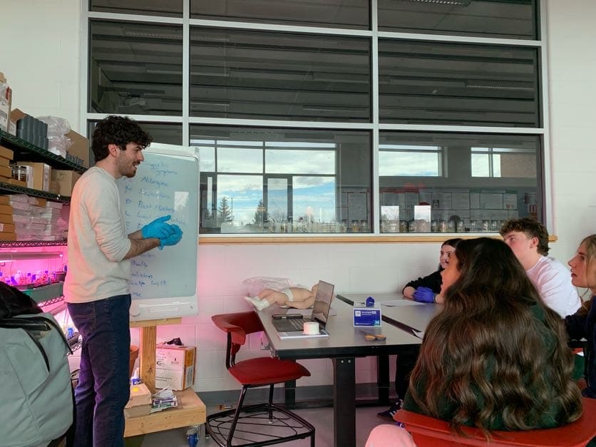 A mentor teaches patient history-taking at a whiteboard while students listen