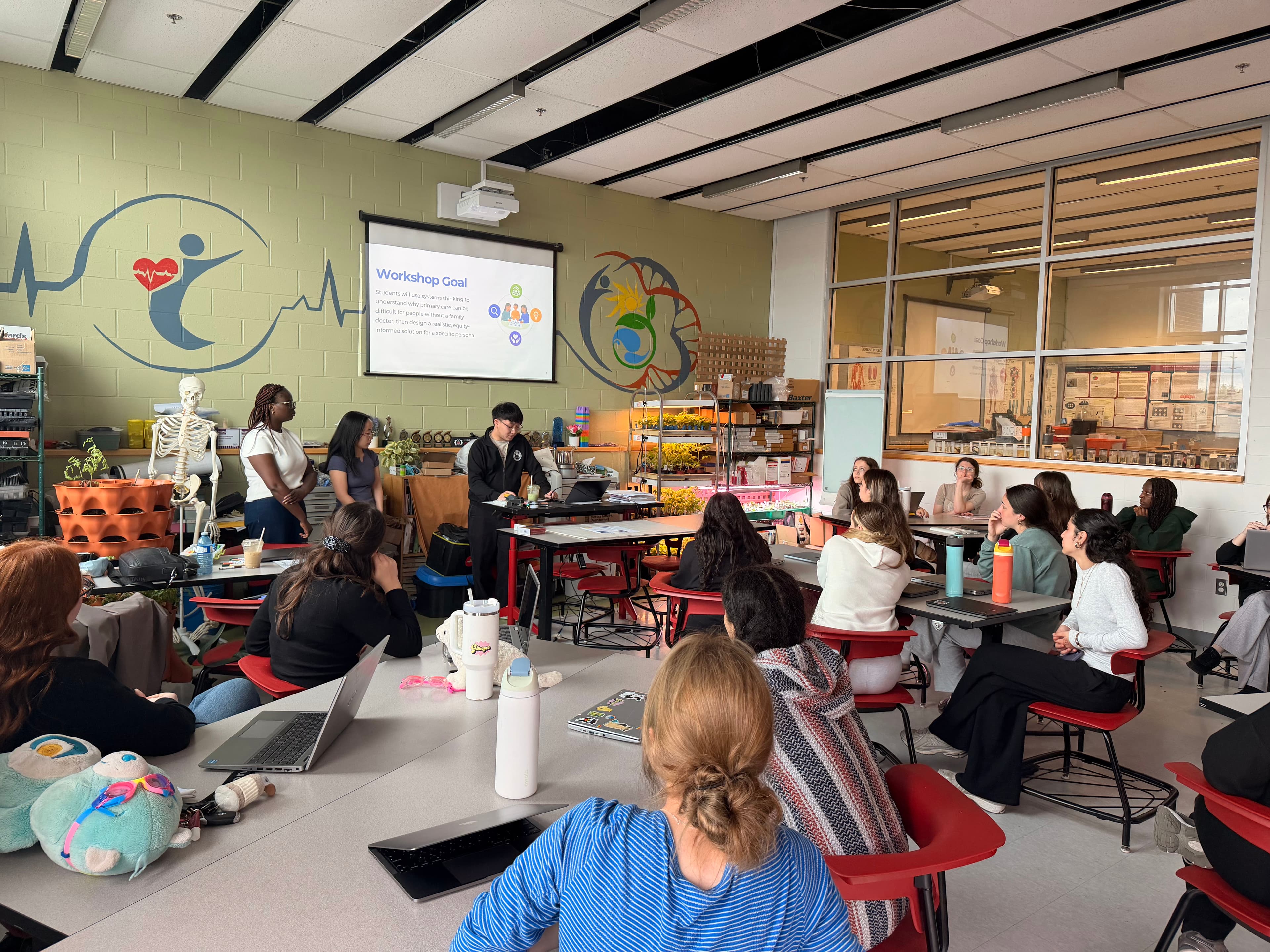 A presenter introduces the workshop goal slide to a full classroom of students